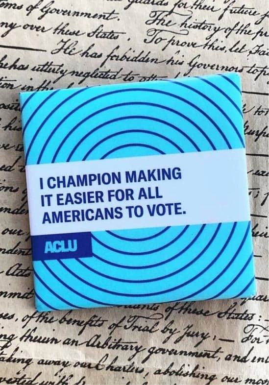 A photo of a button reading "I champion making it easier for all Americans to vote."