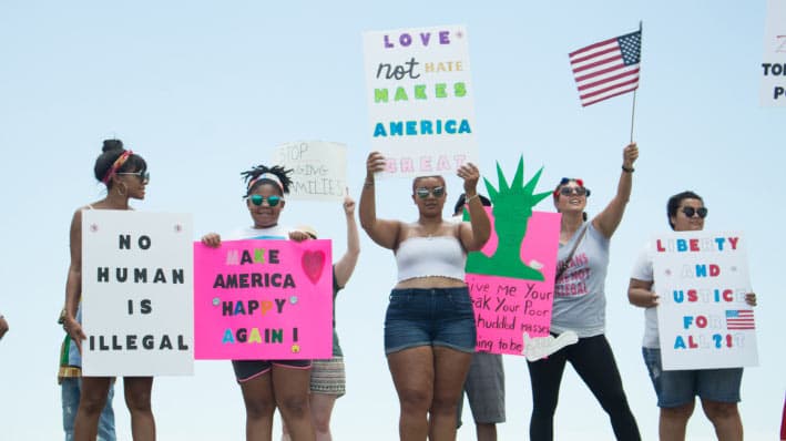 A photo of several protestors holding signs about American ideals.