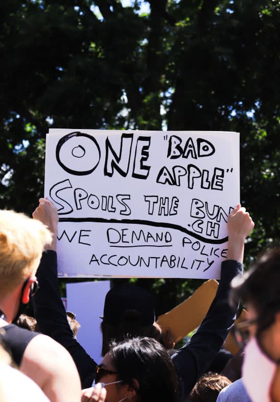 A photo of a protest sign reading "One `bad apple` spoils the bunch. We demand accountability."