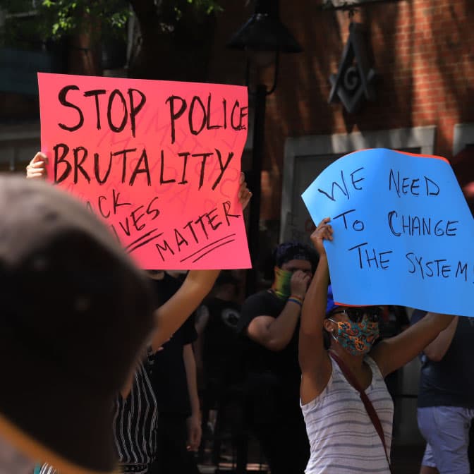A photo of protestors holding signs  advocating for reforming the policing system.